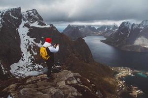 uomo viaggiatore che scatta foto con uno smartphone facendo un'escursione sulla cresta della montagna in norvegia