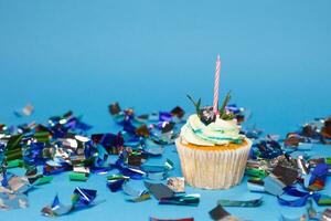 compleanno Cupcake con tre ardente candele al di sopra di blu sfondo foto