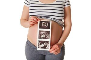 incinta donna in piedi e Tenere sua ultrasuono bambino scansione foto