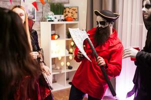 barbuto uomo vestito su piace un' pirata Tenere un ascia mentre celebrazione Halloween con il suo mostro gli amici. foto