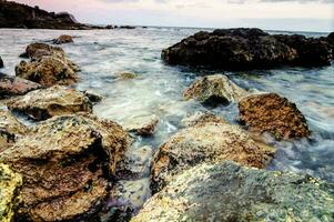 rocce e acqua a tramonto su il spiaggia foto