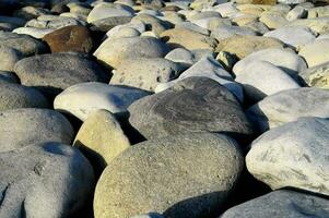 un' grande mucchio di rocce su il spiaggia foto
