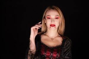seducente biondo donna vestito su piace un' vampiro per Halloween. foto