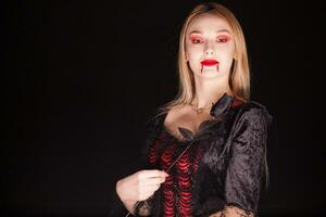 donna indossare un' vampiro costume con un' rosa al di sopra di nero sfondo. foto