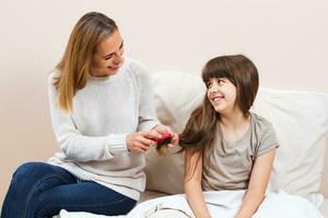 madre pettinatura capelli di sua figlia foto