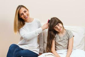 madre pettinatura capelli di sua figlia foto