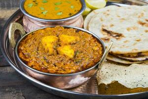 indiano tradizionale thali cibo kadai paneer servito con dal makhani su Vintage ▾ di legno sfondo foto