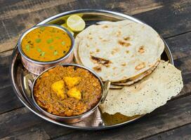 indiano tradizionale thali cibo kadai paneer servito con dal makhani su Vintage ▾ di legno sfondo foto