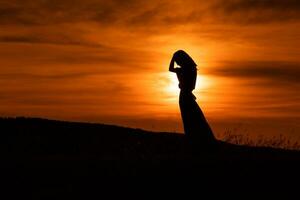 silhouette di un' triste donna in piedi a il tramonto. foto