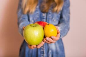 donna Tenere frutta mentre in piedi nel davanti di il parete. foto