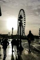 persone a piedi nel davanti di un' Ferris ruota a tramonto foto