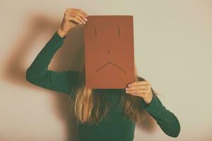 depresso donna con triste viso su carta in piedi solo nel davanti di parete.tonica Immagine. foto