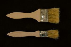 Due dipingere spazzole con di legno maniglie su un' nero sfondo foto