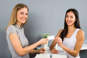 donna addetto alla reception di il fitness centro è dando un' membri carta per sportivo donna chi è venuto per esercizio. foto