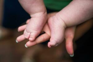 Immagine di poco bambino gambe nel madre mani. messa a fuoco su bambino dita. foto