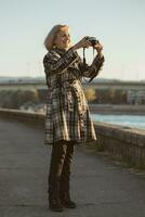 anziano donna gode Fotografare mentre in piedi di il fiume.tonico Immagine. foto