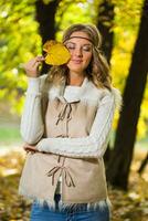 bellissimo boho ragazza Tenere autunno foglia e gode nel il parco. foto