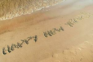contento nuovo anno iscrizione su sabbioso spiaggia con oceano onde nel tropicale Paradiso foto