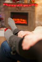 fidanzato Tenere il suo mani su il suo fidanzata piedi festeggiare Natale nel vivente camera. foto