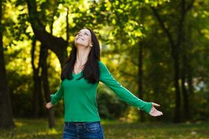 contento donna con braccia disteso gode nel parco foto