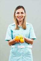 bellissimo infermiera è mostrando frutta. foto
