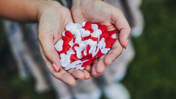 coriandoli di rosso e bianca cuori nel il mani di un' ragazza. foto