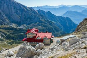 turista con escursioni a piedi zaini nel montagna escursione su estate giorno. uomo viaggiatore escursioni a piedi nel bellissimo montagna paesaggio. scalatore e alpino capanna silvio agostini nel dolomiti Alpi, Italia. foto