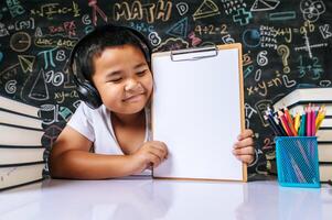 bambino seduto e mostra la lavagna degli appunti in classe foto