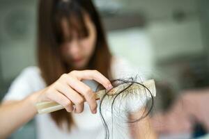 la donna asiatica ha problemi con la caduta dei capelli lunghi attaccata alla spazzola del pettine. foto