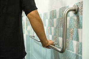 asiatico anziano donna uso bagno maniglia sicurezza nel gabinetto, salutare forte medico concetto. foto