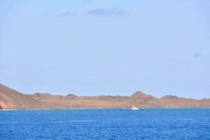 un' barca è su nel il oceano vicino un' roccioso isola foto