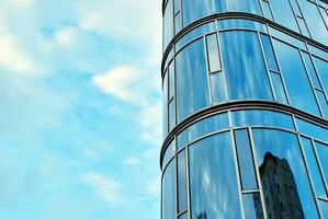 bicchiere edificio con trasparente facciata di il edificio e blu cielo. strutturale bicchiere parete riflettendo blu cielo. astratto moderno architettura frammento. contemporaneo architettonico sfondo. foto