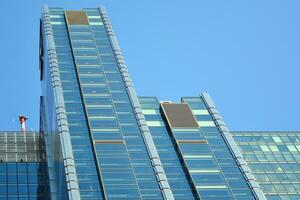 bicchiere edificio con trasparente facciata di il edificio e blu cielo. strutturale bicchiere parete riflettendo blu cielo. astratto moderno architettura frammento. contemporaneo architettonico sfondo. foto