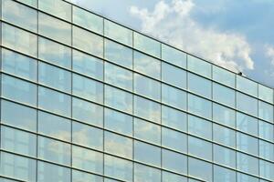 bicchiere edificio con trasparente facciata di il edificio e blu cielo. strutturale bicchiere parete riflettendo blu cielo. astratto moderno architettura frammento. contemporaneo architettonico sfondo. foto