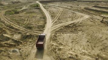 cumulo di rifiuti camion guida su cava la zona. scena. superiore Visualizza di cumulo di rifiuti camion guida attraverso deserto la zona con polveroso superficie a cava. pesante trasporto per cava operazioni foto