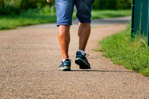 uomo a piedi con scarpe da ginnastica su un' sentiero, avvicinamento di il suo gambe, gli sport attività, salutare lifetsyle foto