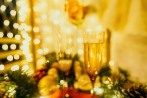 Due Champagne bicchieri pieno con Champagne siamo posto su un' tavolo con un' frutta disposizione. il bicchieri siamo circondato di luci, la creazione di un' festivo atmosfera. foto