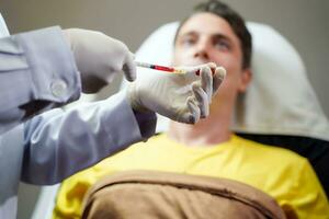 avvicinamento mani di medico nel medico boschetto detiene un' siringa nel preparazione per dare il paziente un iniezione. foto
