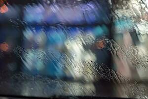 gocce di pioggia su il finestra. acqua gocce su bicchiere. il superficie di bagnato bicchiere. città luci bokeh durante il pioggia. foto