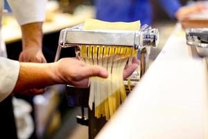 chef che fa la pasta con la macchina, pasta fresca fatta in casa foto