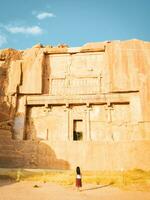 persepoli, iran, 2022 - turista camminare di panoramico lavorato rocce nel Persepolis archeologico luogo. persiano città resti e storia concetto foto