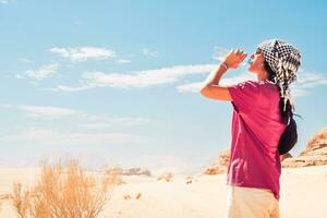 assetato deserto viaggiatore giovane caucasico donna con viso rosso di sole bruciare potabile acqua. lato Visualizza con panorama di caldo deserto foto