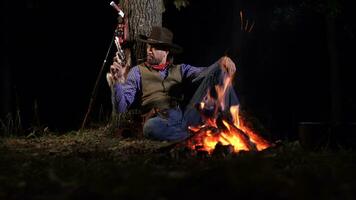 cowboy vicino il fuoco nel il foresta a notte. storico ricostruzione di vita nel il selvaggio ovest di America foto