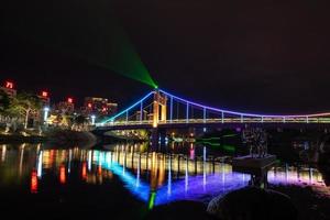 di notte, il ruscello riflette le luci colorate sul ponte foto