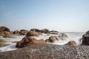 le onde bianche battono contro le rocce nere foto