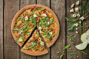 affettato Pizza con prosciutto, gorgonzola, Pera, pino noccioline, rucola foto