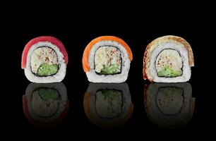 tre Sushi rotoli con salmone, tonno e Anguilla su nero sfondo foto