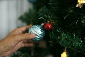 allegro Natale 2024 concetto asiatico donne decorare il Natale albero con colorato Natale palle. foto