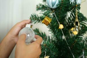 allegro Natale 2024 concetto asiatico donne decorare il Natale albero con colorato Natale palle. foto