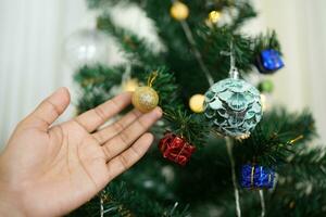 allegro Natale 2024 concetto asiatico donne decorare il Natale albero con colorato Natale palle. foto